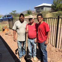 Three workers posed in dungarees and with a shovel